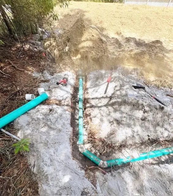 New green PVC sewer line laid in an excavated trench