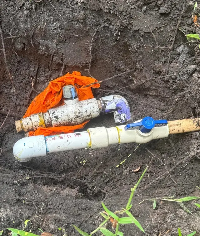 Water line valve repair with blue shutoff valves in a yard trench